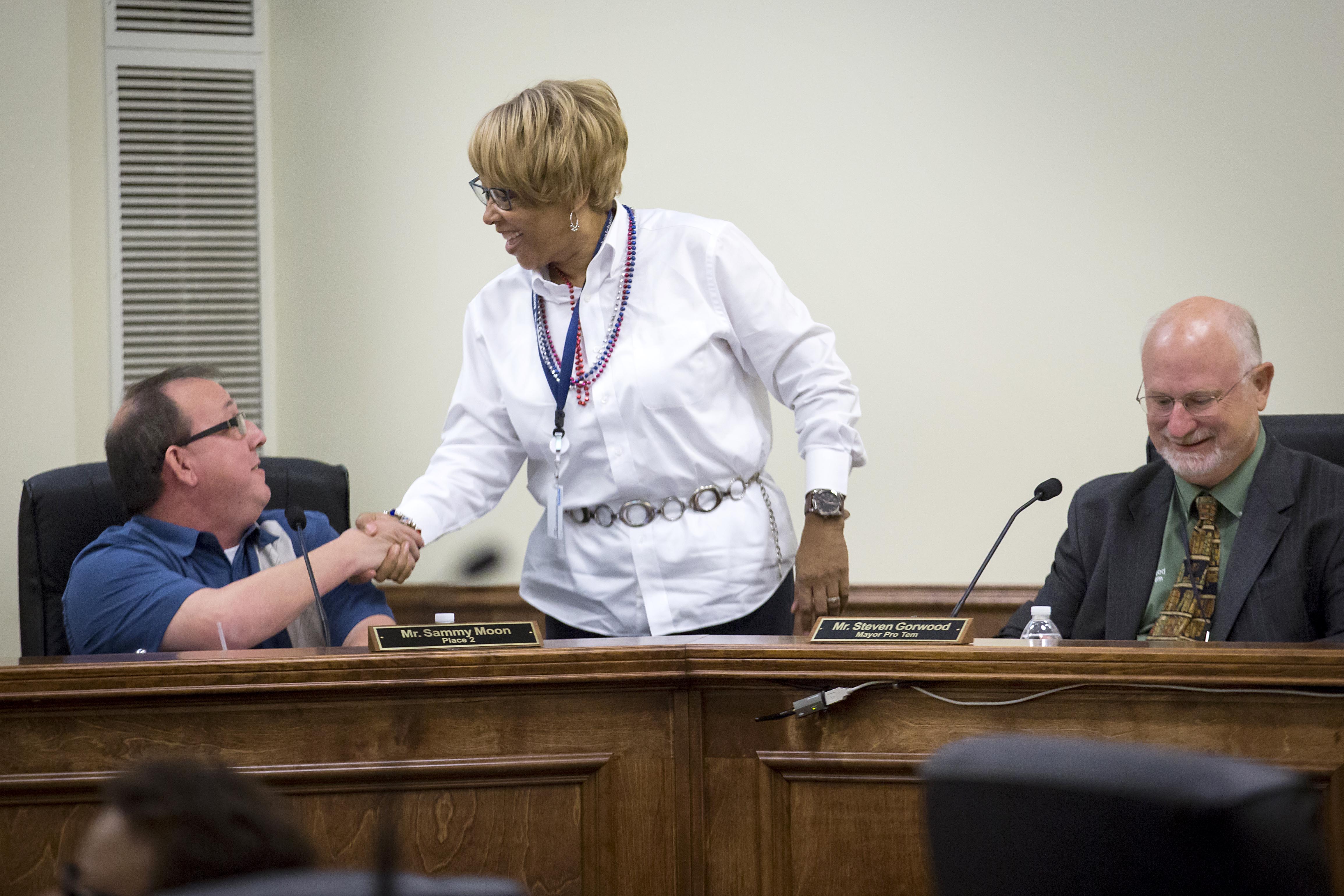 Balch Springs City Council member Wanda Adams shakes hands with council member Sammy Moon as Mayor Pro Tem Steven Gorwood prepares for a council meeting on Monday