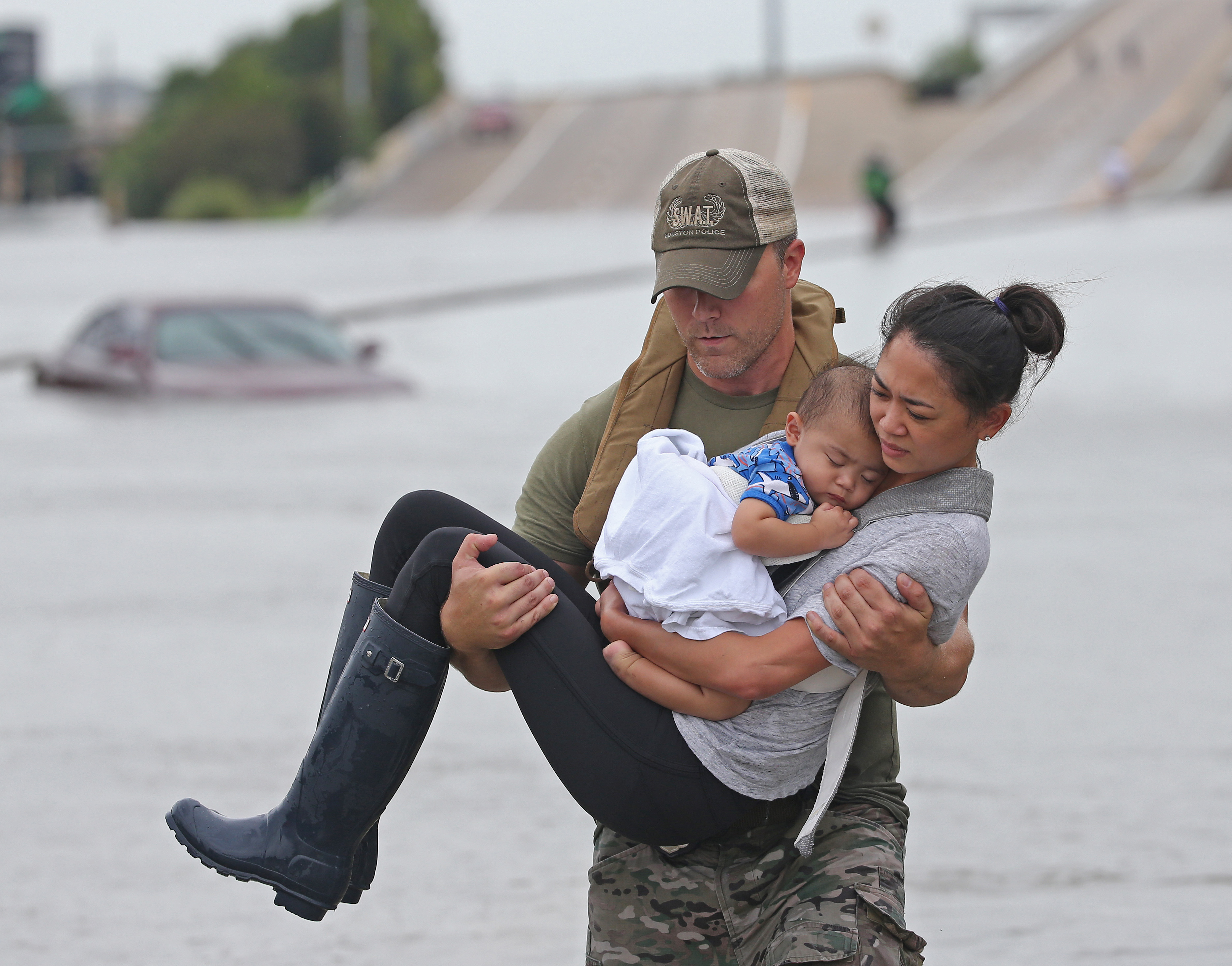 Houston SWAT officer Daryl Hudeck carries Catherine Pham and her son 13-month-old son, Aiden, to safety after they were rescued via boat Sunday from the flooding on Interstate 610 south in Houston.(Louis DeLuca/Staff Photographer)