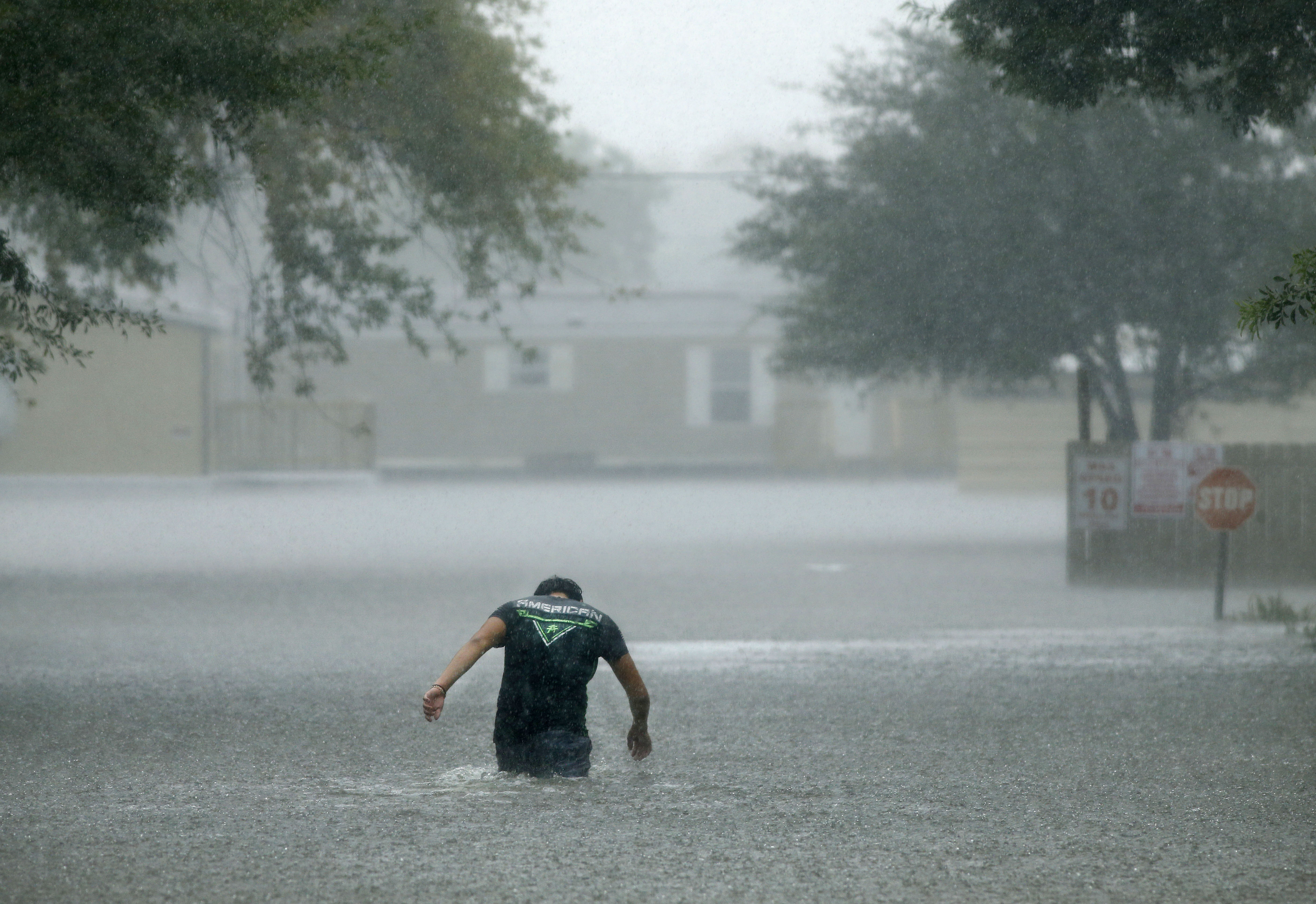 In a driving rainstorm Sunday, a man heads back into the flooded Pearland Acres Mobile Home Community to try to save people's belongings.&nbsp;(Tom Fox/Staff Photographer)