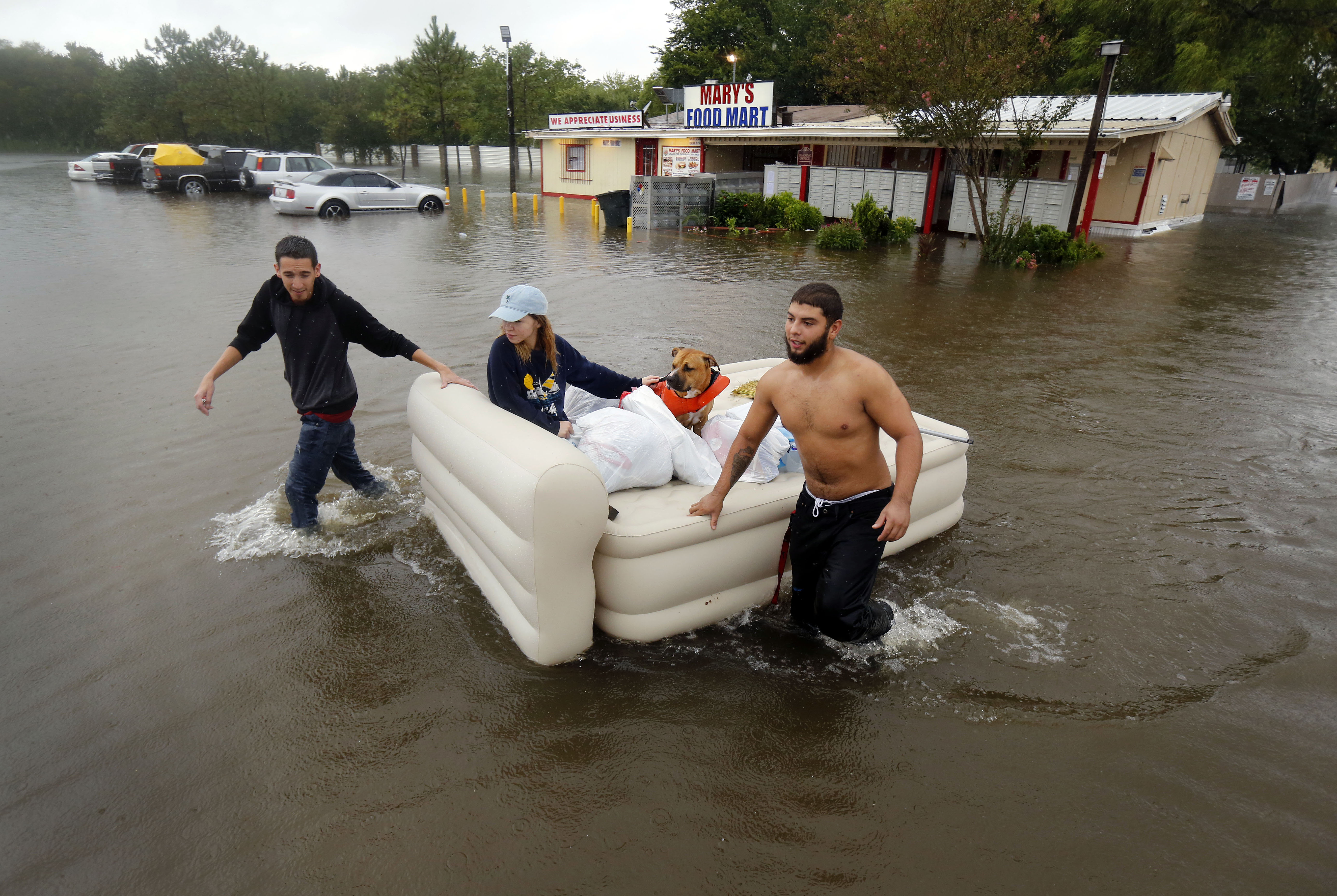 Cristopher Cardona (left) and Dario Munoz (right) guide Rachel Beck and her dog, Blaze, to safety aboard an inflatable bed Sunday at Pearland Acres Mobile Home Community in Pearland. Dario says, "That's what I sleep on."(Tom Fox/Staff Photographer)