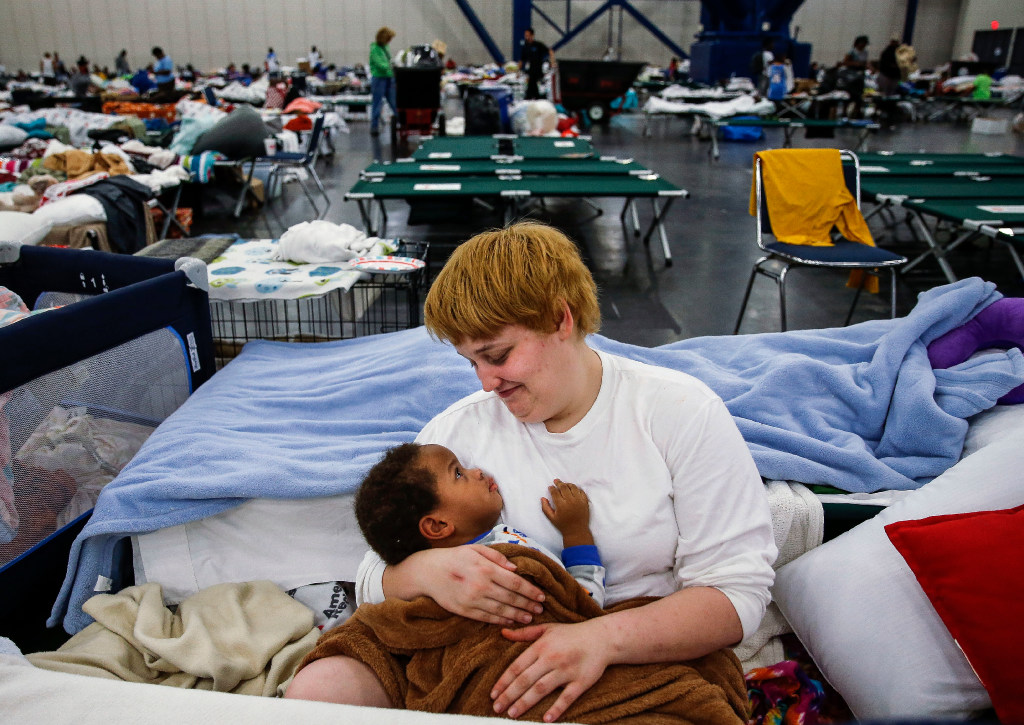 Shiann Barker holds her nephew Brayln Matthews Sims Jr. 1 between cots at the George R. Brown Convention Center where nearly 10,000 people are taking shelter after Tropical Storm Harvey Wednesday Aug. 30 2017 in Houston. They have ben at the shelter