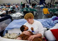 ShiannBarker holds her nephew, Brayln Matthews Sims Jr., 1, between cots at the George R. Brown Convention Center, where nearly 10,000 people took shelter in Houston.(Michael Ciaglo/Houston Chronicle)