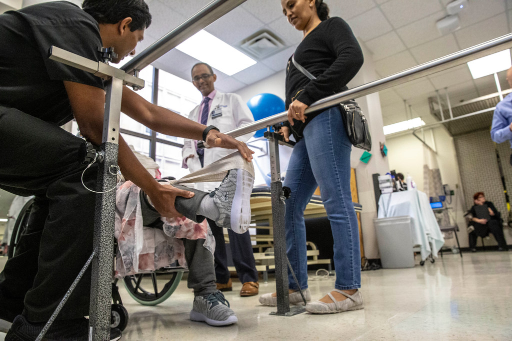Physical therapist Binu Aramath (left) helps Hareg Wolde's mother as neurologist Dr. Mehari Gebreyohanns and Wolde watch at Parkland Hospital in Dallas.&nbsp;(Carly Geraci/Special Contributor)